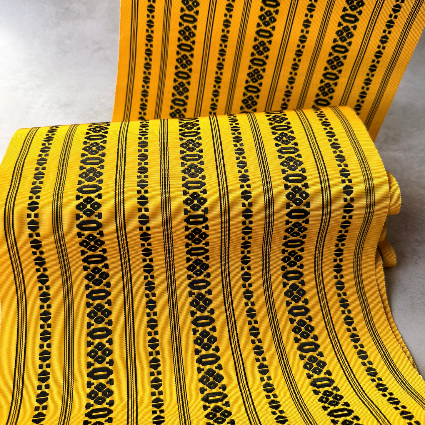 Draped view of antique yellow and black hachisun obi fabric