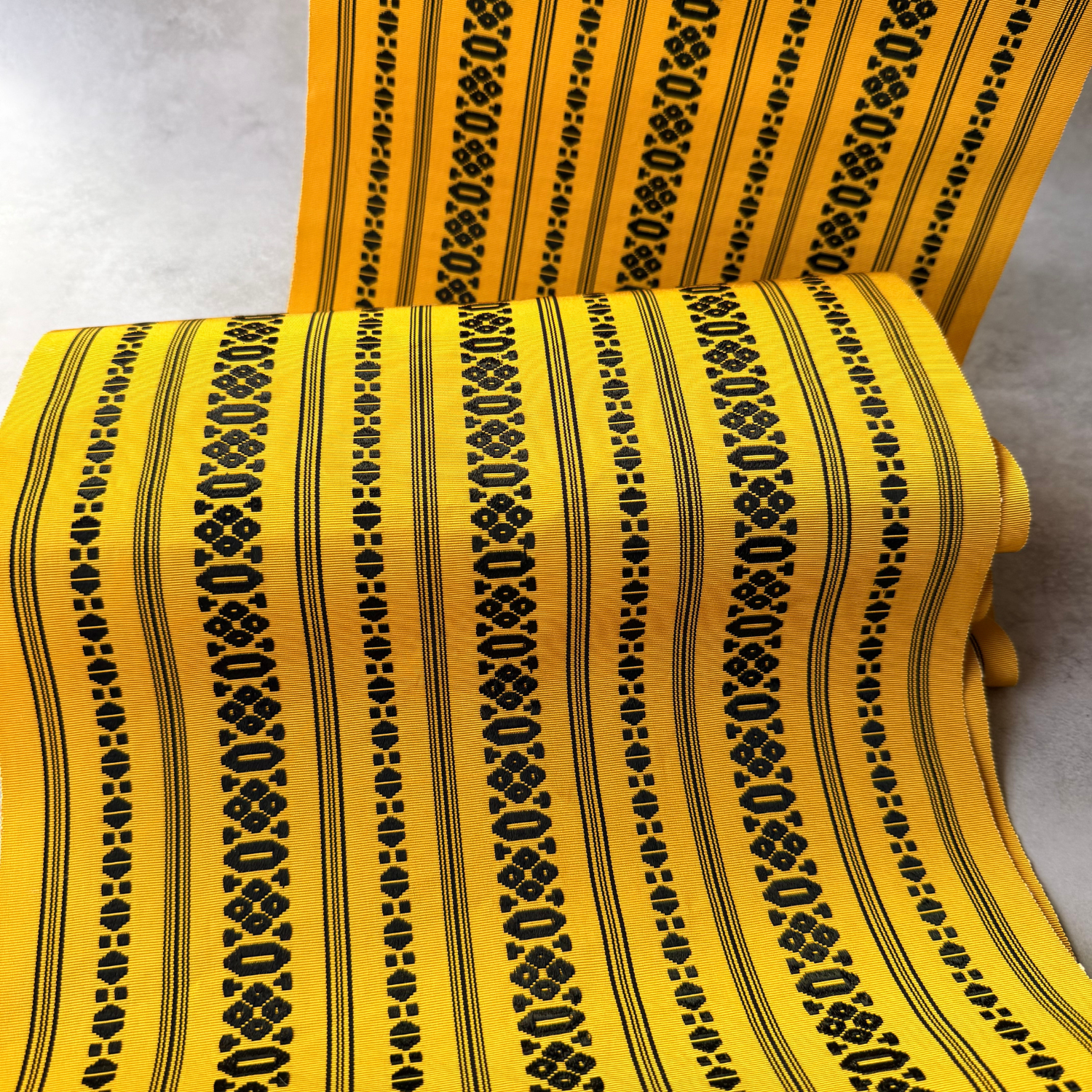 Draped view of antique yellow and black hachisun obi fabric