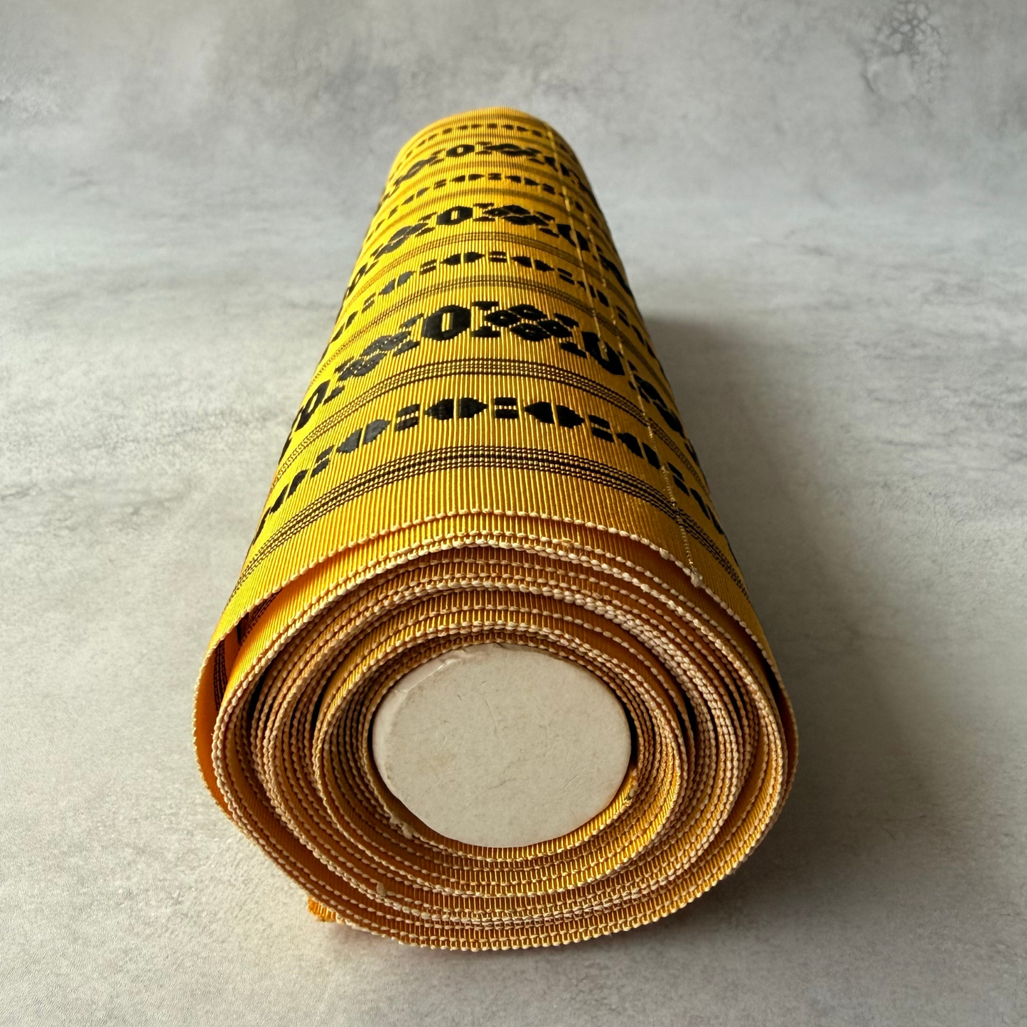 End view of yellow and black Japanese obi fabric roll