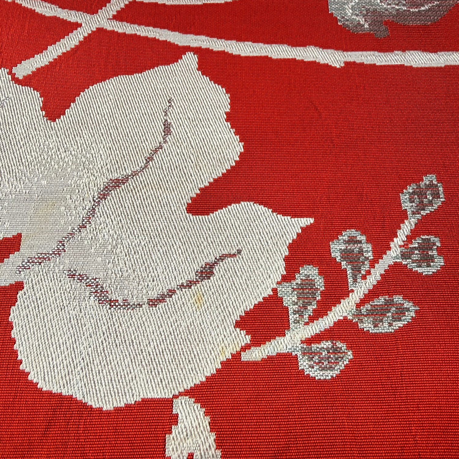 Close-up of pale woven ivy leaves on reddish brown obi fabric