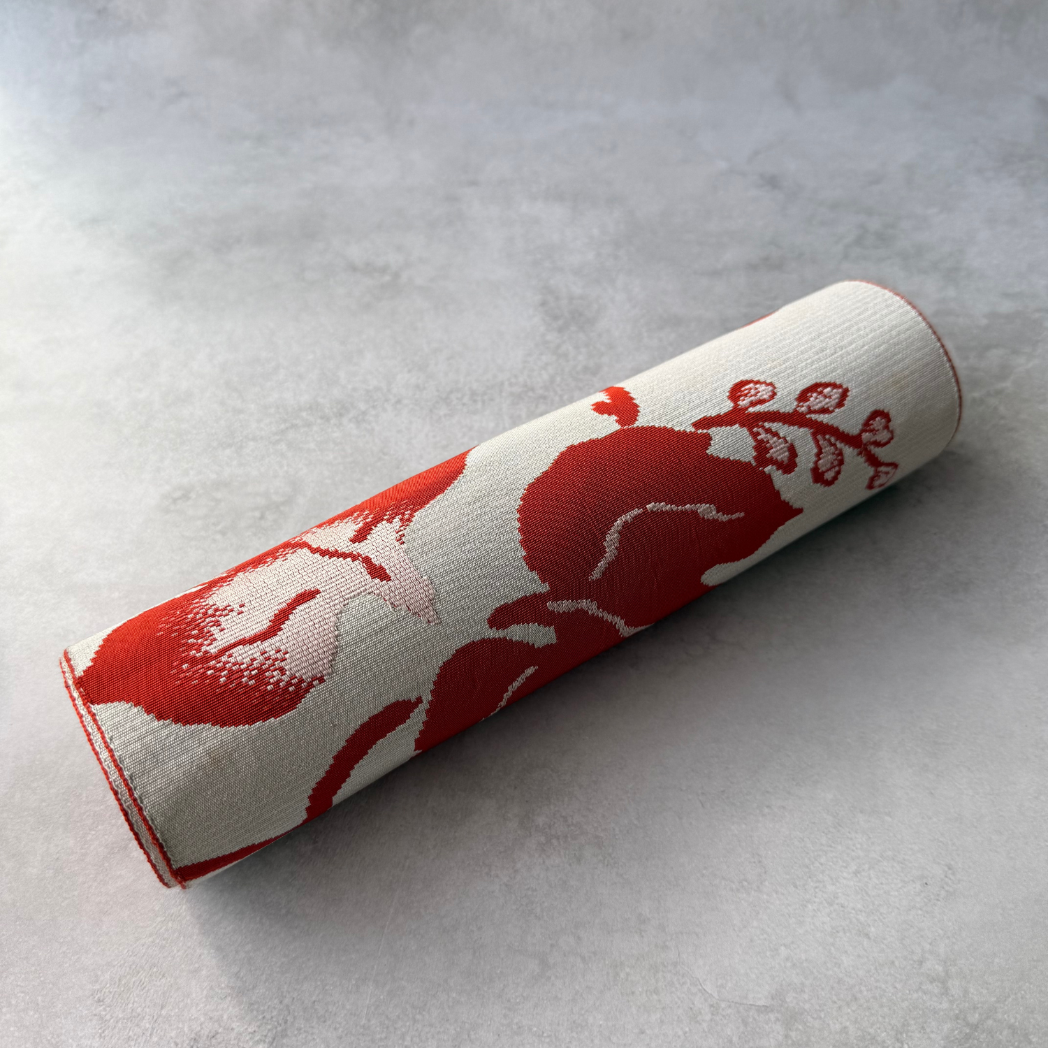 Rolled view of antique reddish brown and ivory hachisun obi fabric