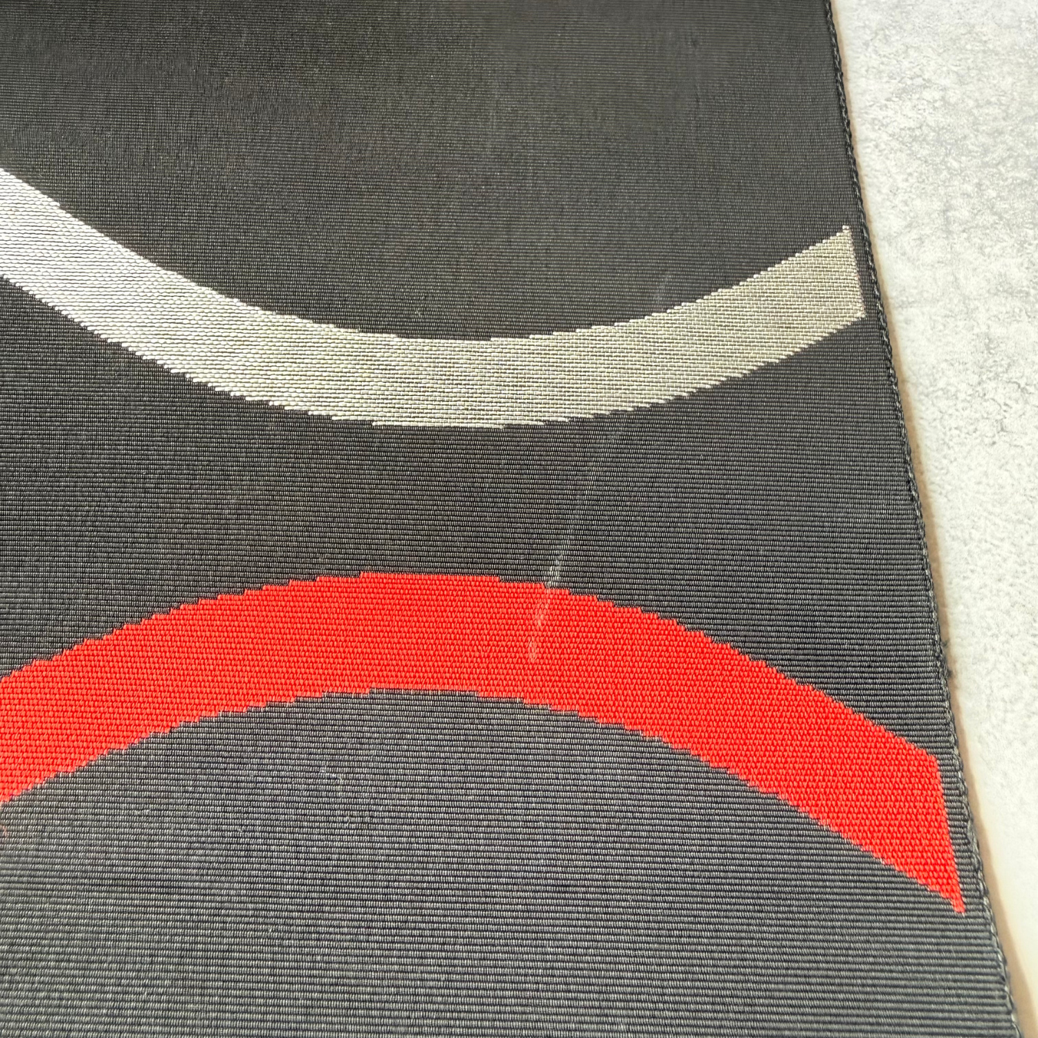 Close-up of silver and red woven wave motifs on black obi fabric