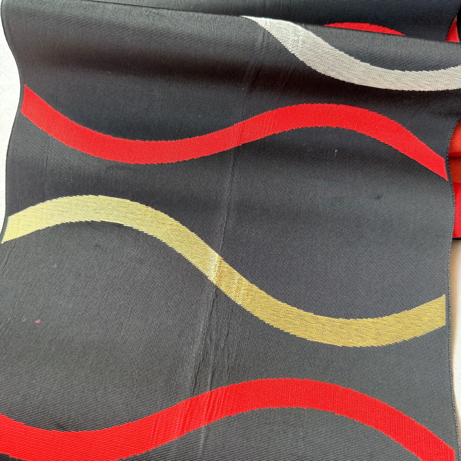 Detailed view of alternating red gold and silver wave bands
