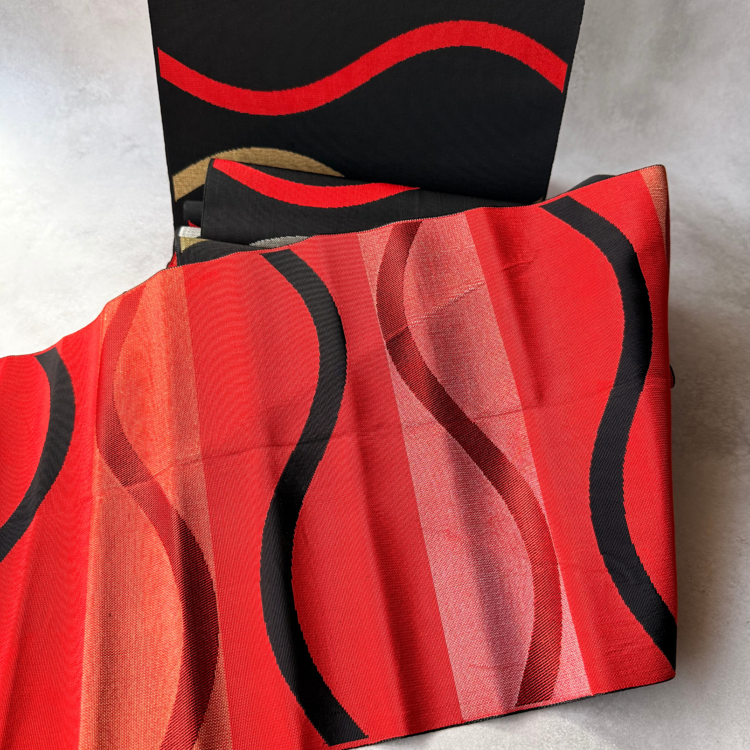 Draped view showing black and red sides of antique hachisun obi fabric