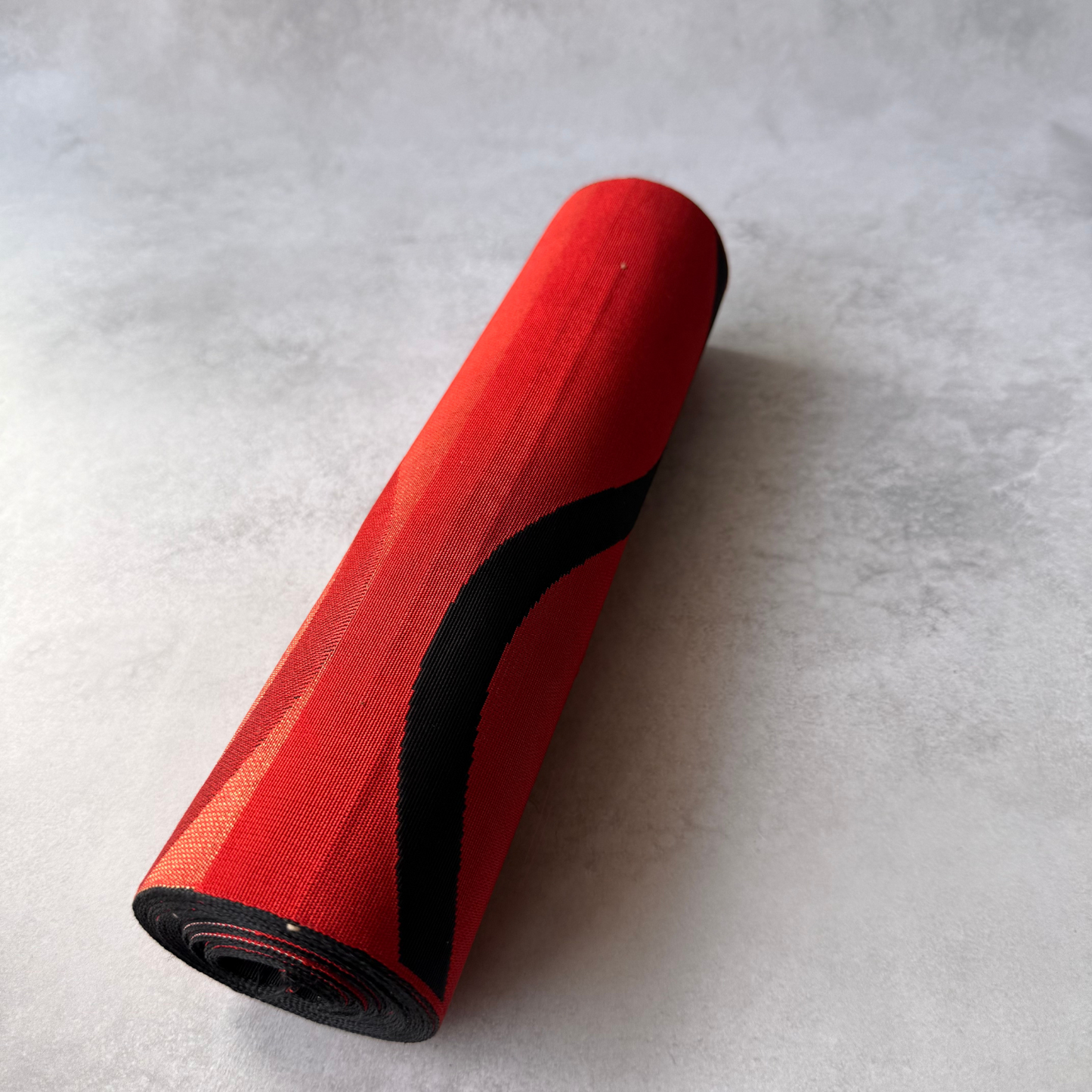Rolled view of antique red and black Japanese obi fabric