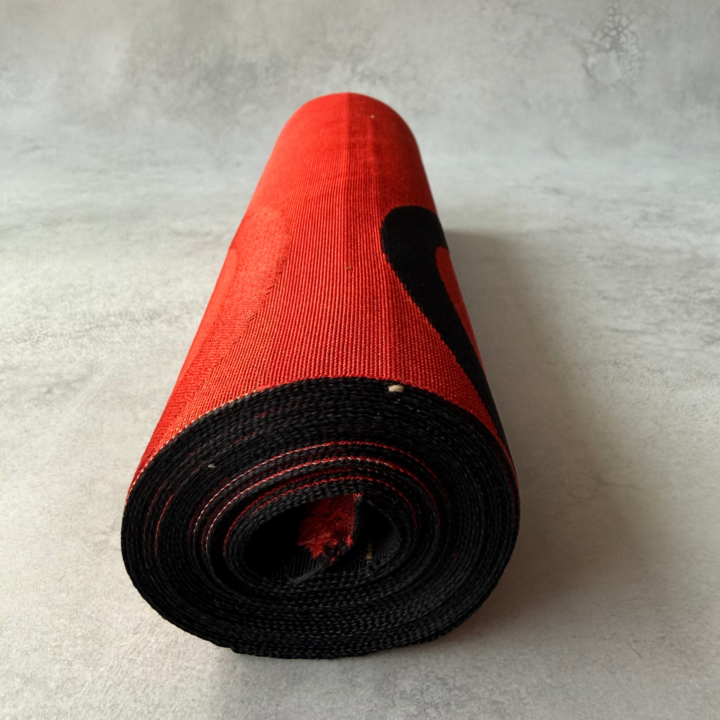 End view of antique black and red hachisun obi fabric roll