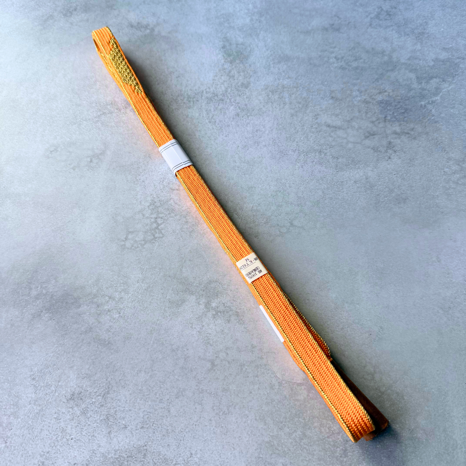 Reverse side and original labels of an unused vivid orange silk Korai-gumi obijime