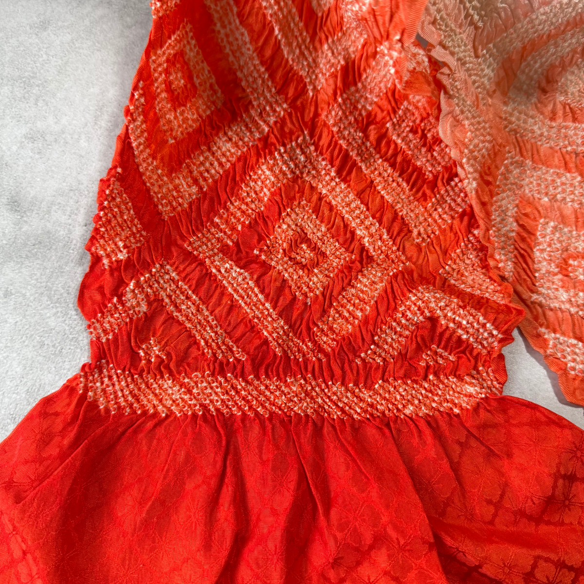 Close-up of vermilion red silk obiage with white shibori diamond pattern