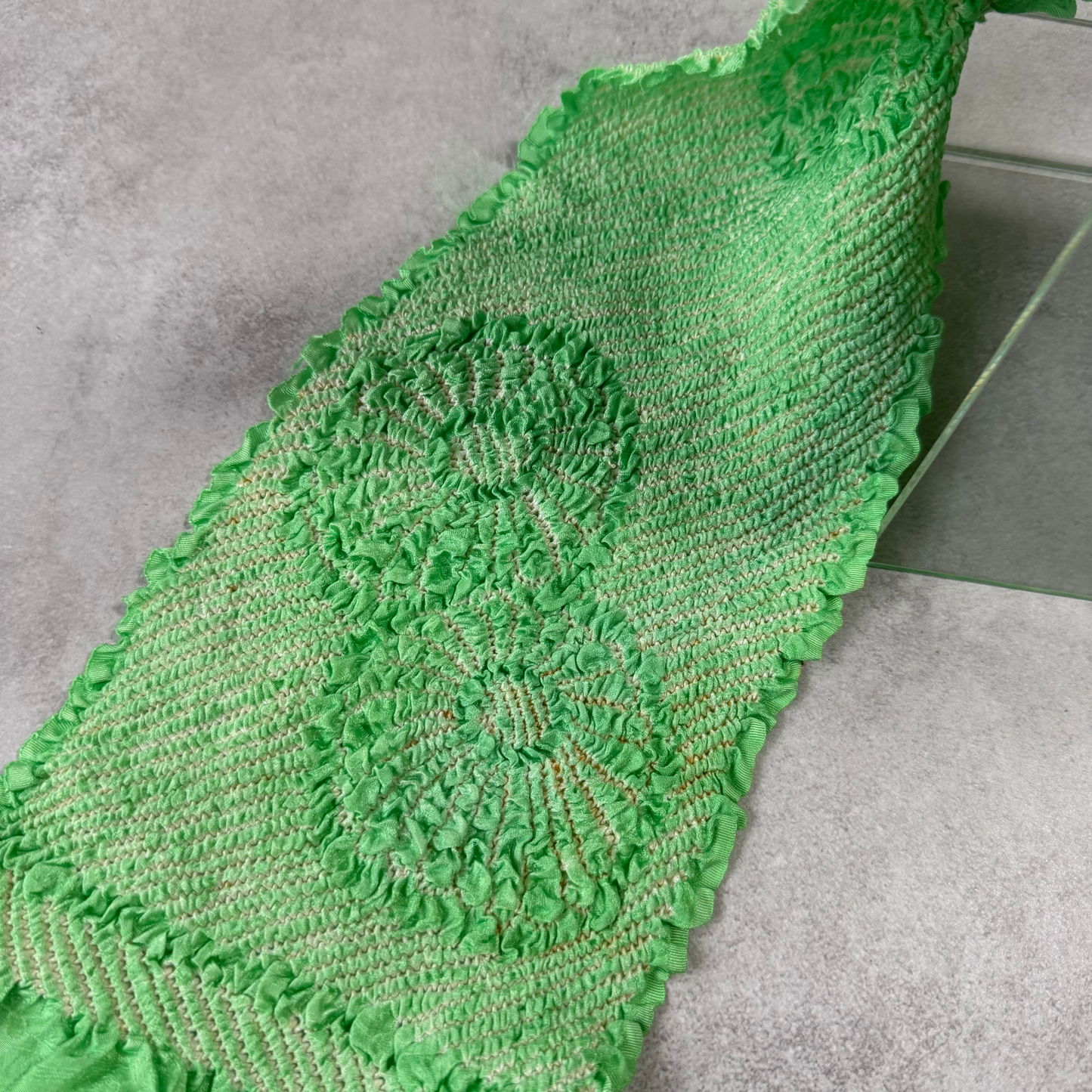 Close-up showing a large floral shibori design and condition details on green silk
