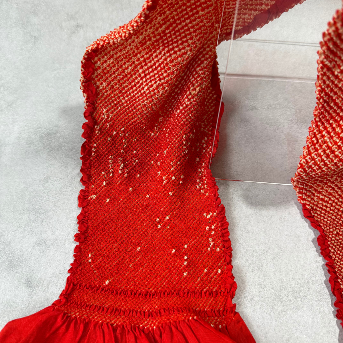 Detailed view of scattered ivory shibori accents and condition on a vintage red silk obiage