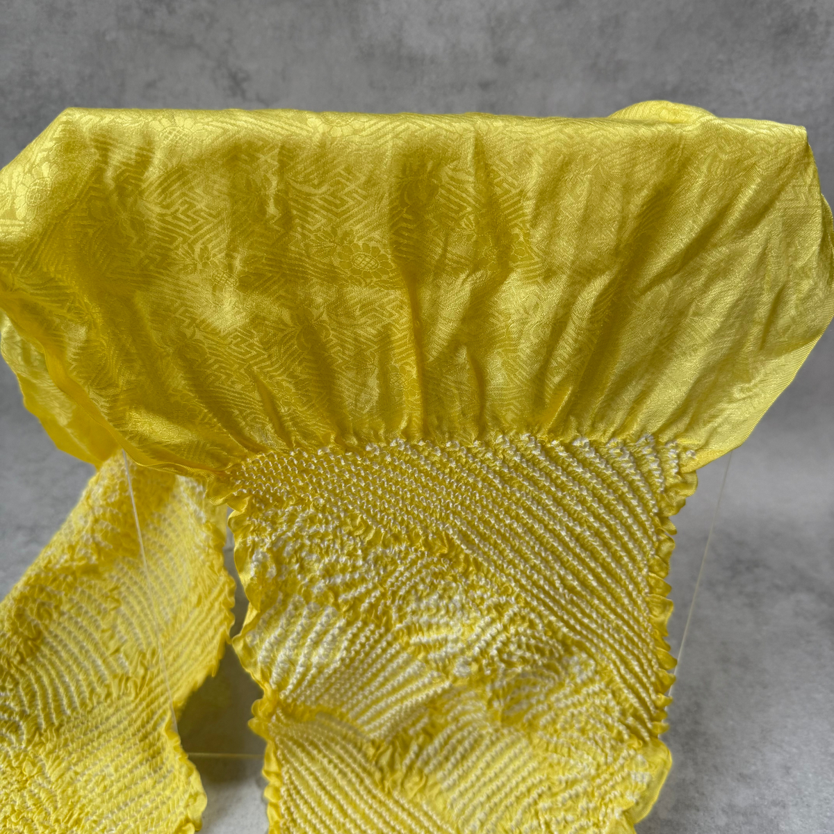 Close-up of floral and geometric jacquard patterns woven into lustrous yellow silk